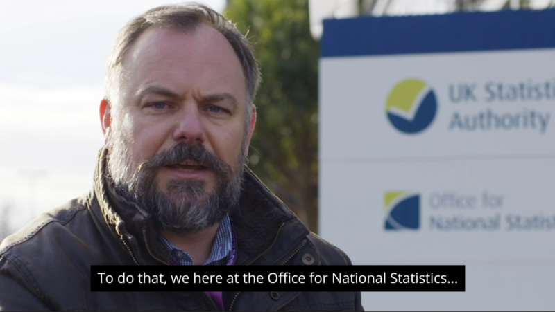 Captions added in white text on a black background to a video screenshot of a man talking to camera outside of an ONS building.